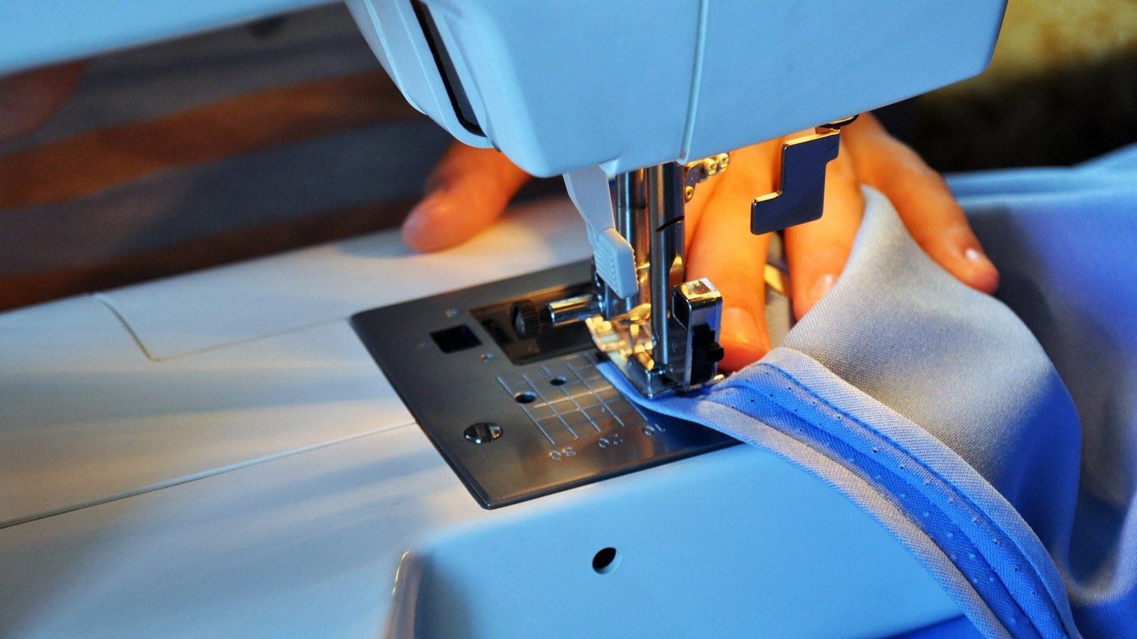 Gros plan sur une machine à coudre professionnelle guidant un tissu bleu