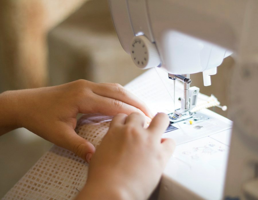 Mains guidant un tissu sous le pied-de-biche d’une machine à coudre